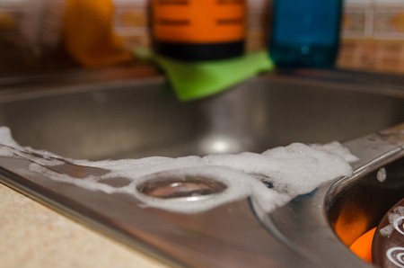 dirty sidhes inside the sink with with foam from dish soap close up viewの写真素材
