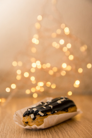 chocolate eclair with boken lights. sweet dessert on the wooden table in the coffee shopの写真素材