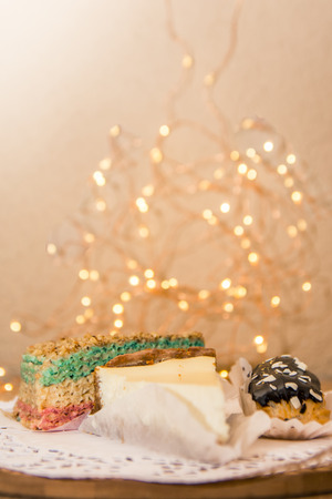 different desserts on the wooden table with bokeh lights background. A slice of sheesecake, chocolate eclair and waffle cake for menu in coffee shopの写真素材