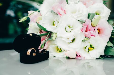 wedding rings in opened black box with bride bouquet on the backgroundの写真素材
