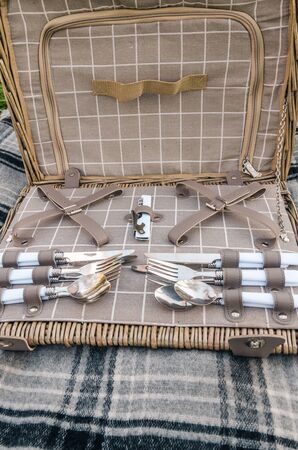 opened picnic basket with silver cutlery on the grey blanketの写真素材