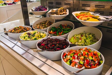buffet table with salats and  vegetables in big white plates.の写真素材
