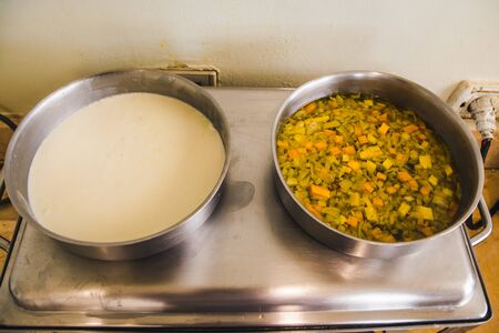 bowls with ingredients on the stove. boling milk and vegetablesの写真素材