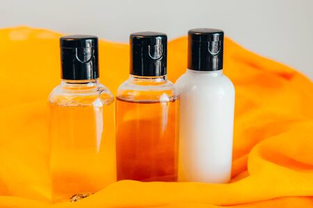close up view of shower gel, shampoo and body lotion in small travel tubes in hotel bathroom on orange towelの写真素材