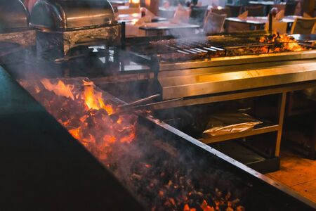 frying meat on fire in hotel or restaurant kitchen with smoke coming upの写真素材
