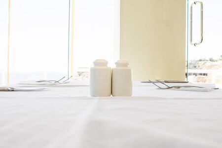white salt and papper shakers on the set table at the restaurantの写真素材