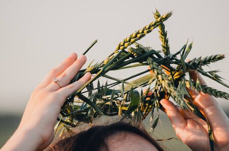 woman is putting on handmade wreath made of green wheat