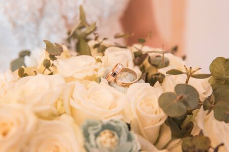 two golden wedding rings lie on the bouquet of flowersの写真素材
