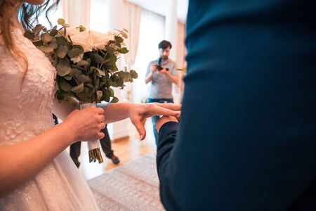 Groom slipping ring on finger of his bride at wedding dayの写真素材