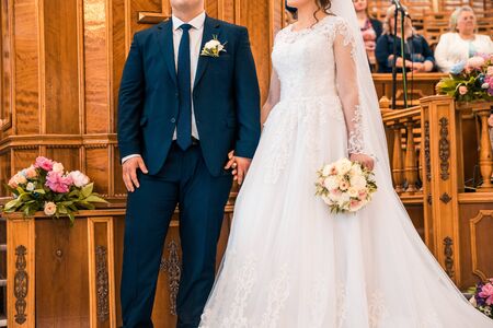 bride and groom standing close and holding hands at the weddingの写真素材