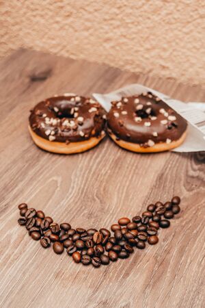 smiling face with donuts and coffee beans. chocolate makes you happy concept. good vibes at the coffee shopの写真素材