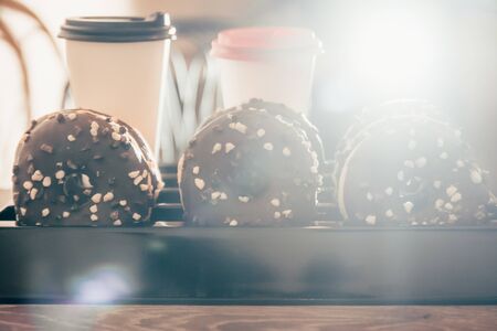 chocolate donuts with takeaway coffee at the coffee shop with bokeh light on the backgroundの写真素材