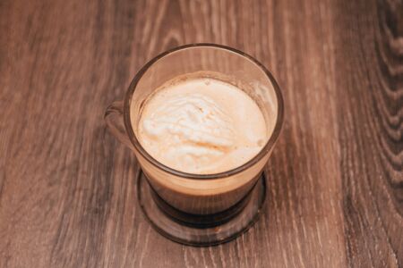 a cup of dark coffee with foam on the wooden table from top view. drinking only coffee for breakfastの写真素材