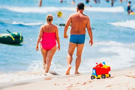 a chubby couple in swimsuit walking on the beach. eating fast food limitationsの写真素材
