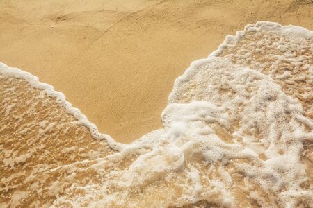 background of wave foam on the yellow  sand beachの写真素材