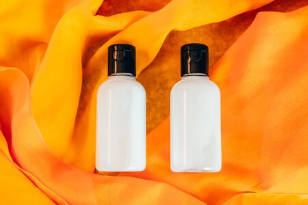two travel bottles of body lotion on orange backgroundの写真素材
