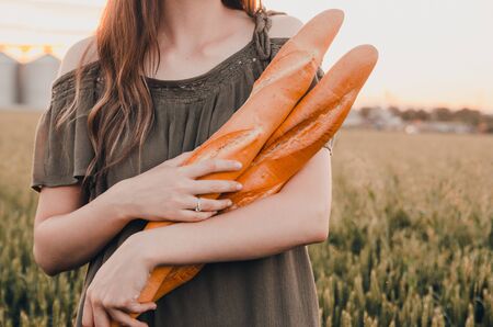 woman holds freshmade french baguettes in wheat fieldの写真素材