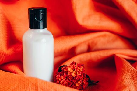 close up view of body lotion in small travel tube in hotel bathroom on orange towelの写真素材