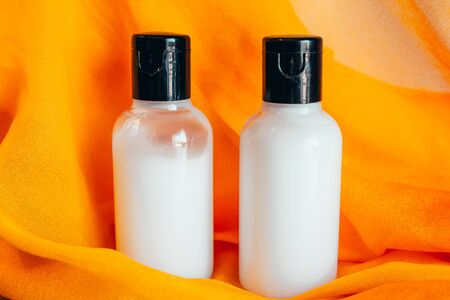 close up view of shower gel and body lotion in small travel tubes in hotel bathroom on orange towelの写真素材