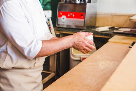 cooker in special uniform kneads the dough in his hands. bakery conceptの写真素材