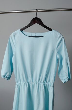 close up view of light blue dress hanging on dressing rail with isolated background. pastel colors of clothes in fashion design studio or sewing workshopの写真素材