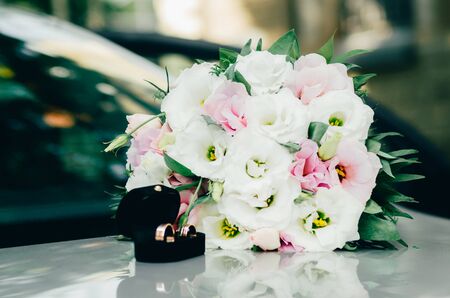 wedding rings in opened black box and white bride bouquet on the car. wedding moments backgroundの写真素材