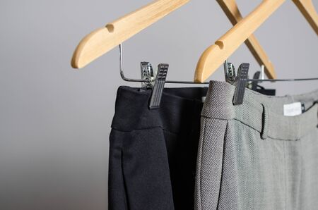 close up view black and grey female pans on hangers with isolated background. new collection of office clothes from sewing factory designed in fashion studioの写真素材