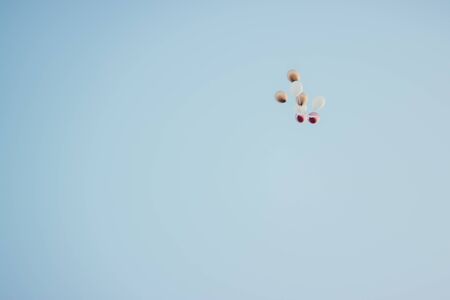 white balloons flying away in the skyの写真素材