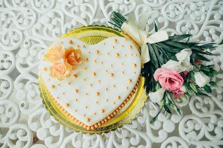 wedding bouquet with cake in the shape of a heart on the table from top viewの写真素材