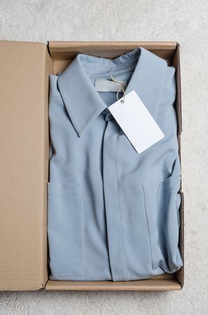 light blue dress in a cardboard box with mock label to write your logo . home delivery of odered clothes from top view. unpacking the packageの写真素材