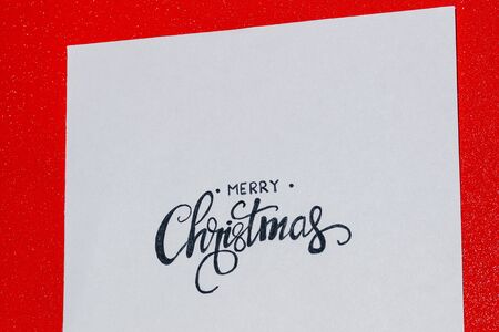 red background of merry christmas written on paperの写真素材