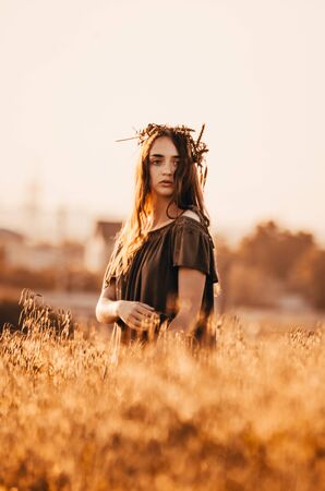 close up photo of woman in green dress standing in golden wheat fieldの写真素材