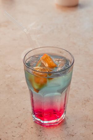 pink and blue cooling cocktail with slices of orangeの写真素材