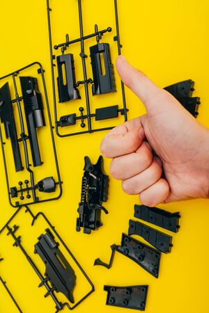 assemble toy handgun with bulllets from the parts concept on yellow background. Plastic model part kits  from top view.の写真素材