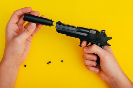mans hands assembling toy handgun with bulllets from the parts from top viewの写真素材