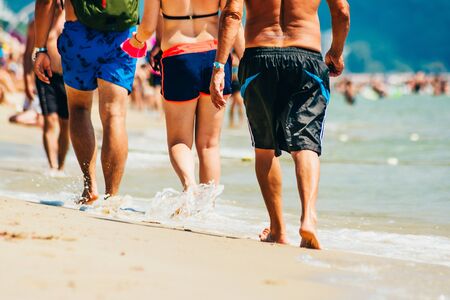 many people walking on the beach. peoples moving legs by the seaの写真素材