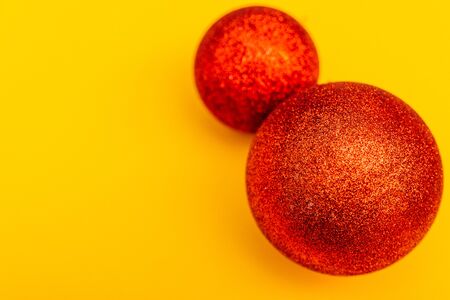 two red christmas tree balls isolated on yellow background from top viewの写真素材