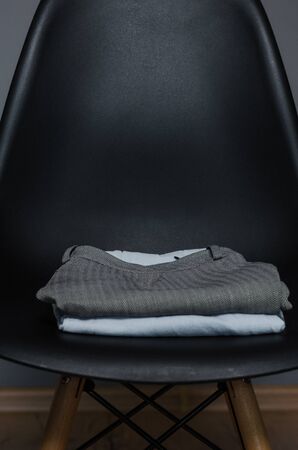 close up view of black chair with a pile of new designed clothes in fasion studio.の写真素材