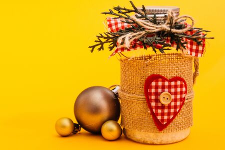 christmas decorated jar with balls on yellow background. selective focusの写真素材