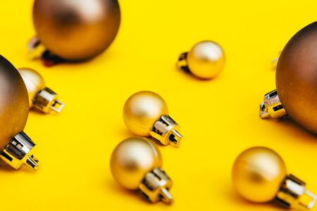 golden christmas tree balls of different sizes. new year decoration in yellow color backgroundの写真素材