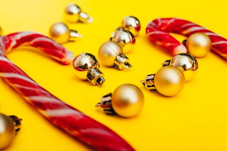 christmas decor on yellow background. christmas golden tree balls and peppermint candy canes. selective focusの写真素材