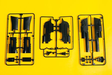 assemble toy handgun with bulllets from the parts concept on yellow background. Plastic model part kits  from top view.の写真素材