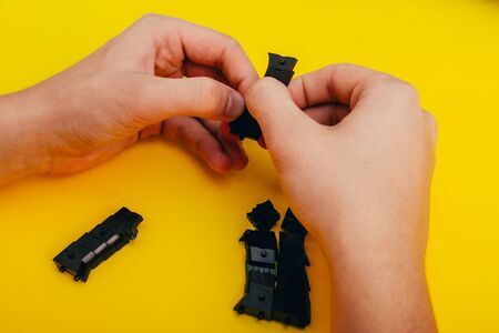 mans hands assembling toy handgun with bulllets from the parts from top viewの写真素材