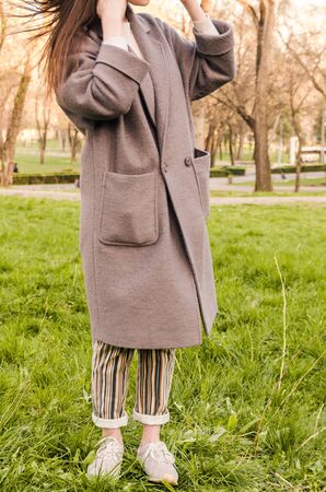 women look or outfit with long grey coat outside in the parkの写真素材