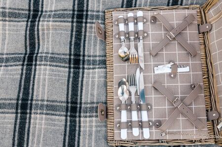 opened picnic basket with silver cutlery on the grey blanket from top viewの写真素材