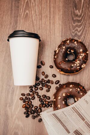 background of takeaway coffee cup with chocolate donuts on the wooden table. breakfast at the coffee shop conceptの写真素材