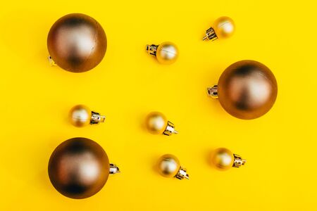 golden christmas tree balls of different sizes. new year decoration in yellow color backgroundの写真素材
