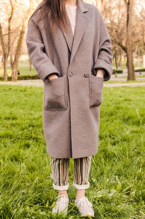 women look or outfit with long grey coat outside in the parkの写真素材