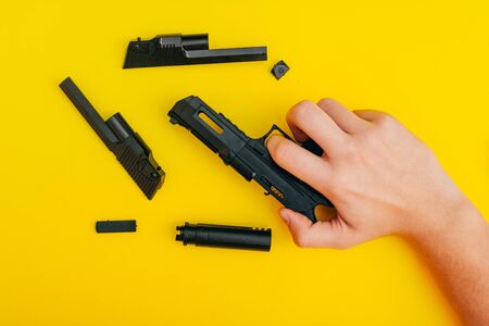 mans hands assembling toy handgun with bulllets from the parts from top viewの写真素材
