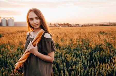 woman holds french baguette in wheat fieldの写真素材
